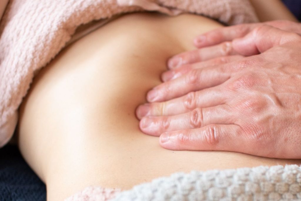 Mains d'un fasciathérapeute pratiquant le massage Chi Nei Tsang, technique promue par Nicolas Luc Levé.