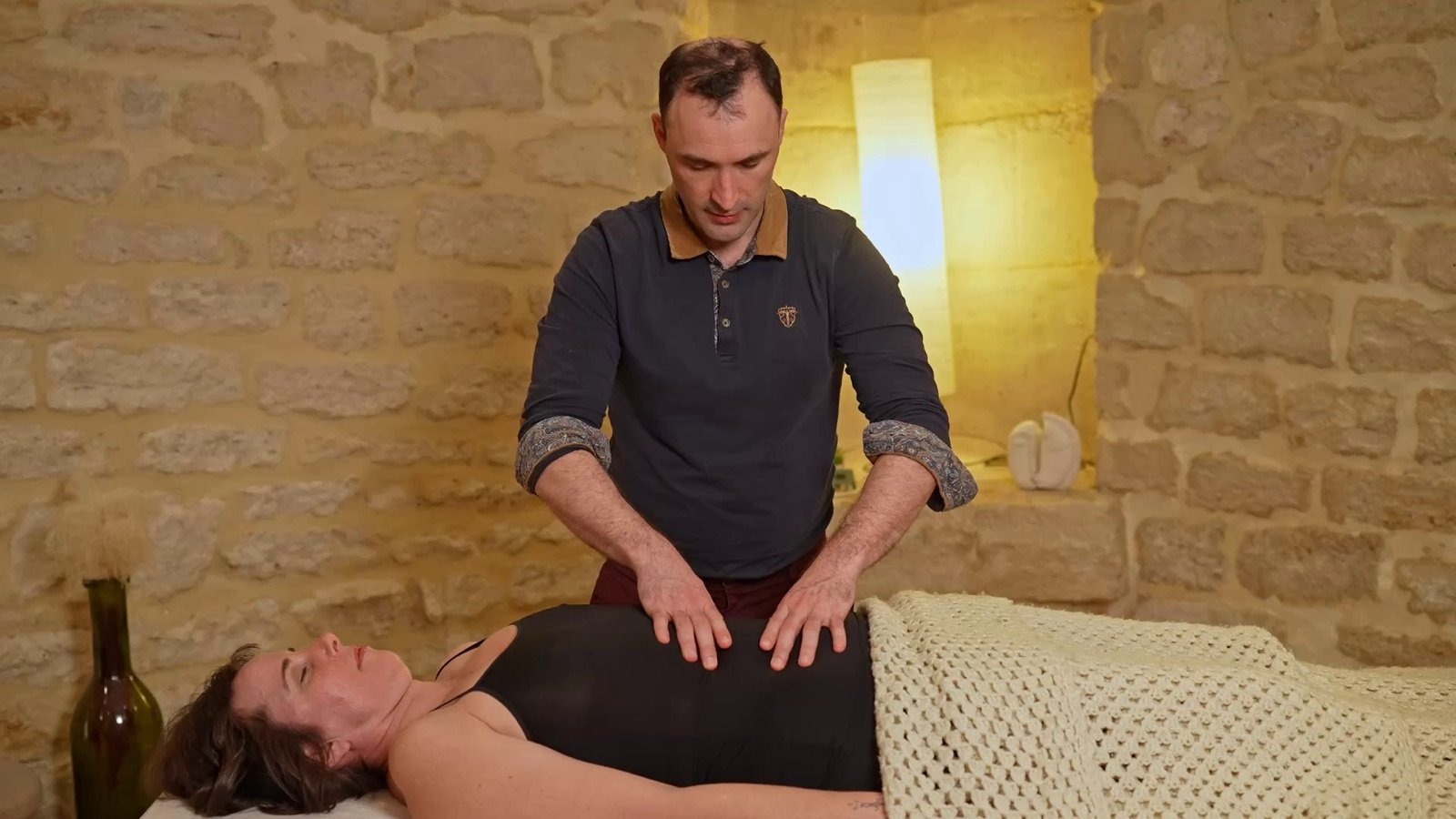 Nicolas Luc Levé pose les deux mains à plat sur l'abdomen d'une personne allongée, pour écouter les fascias du ventre