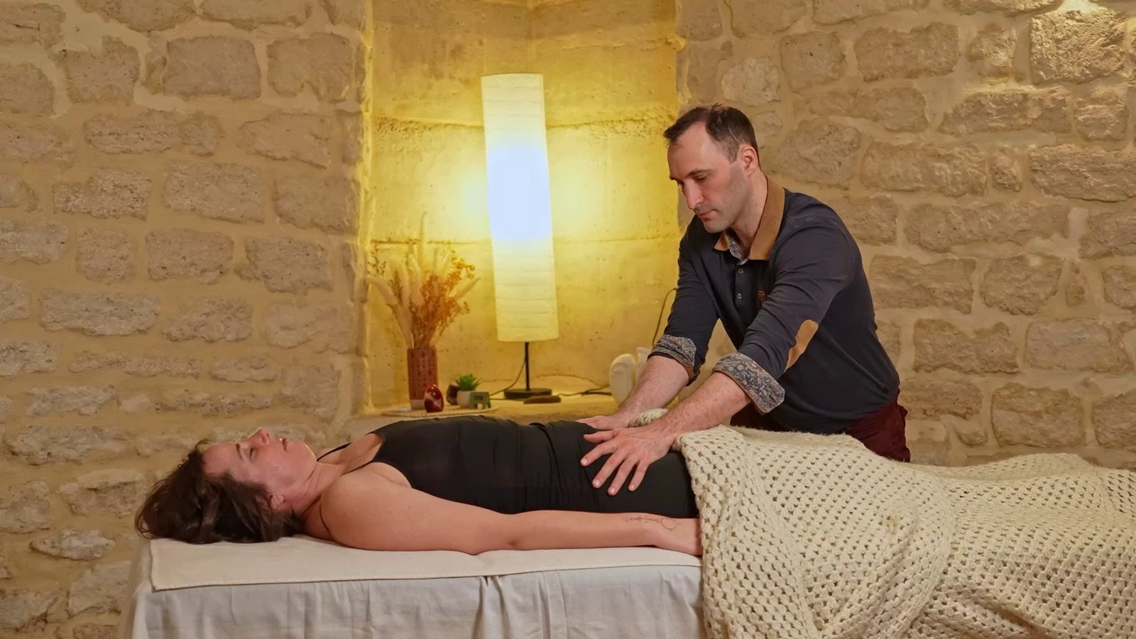 Massage abdominal doux sur le côté du ventre d'une personne allongée, pour accompagner le transit